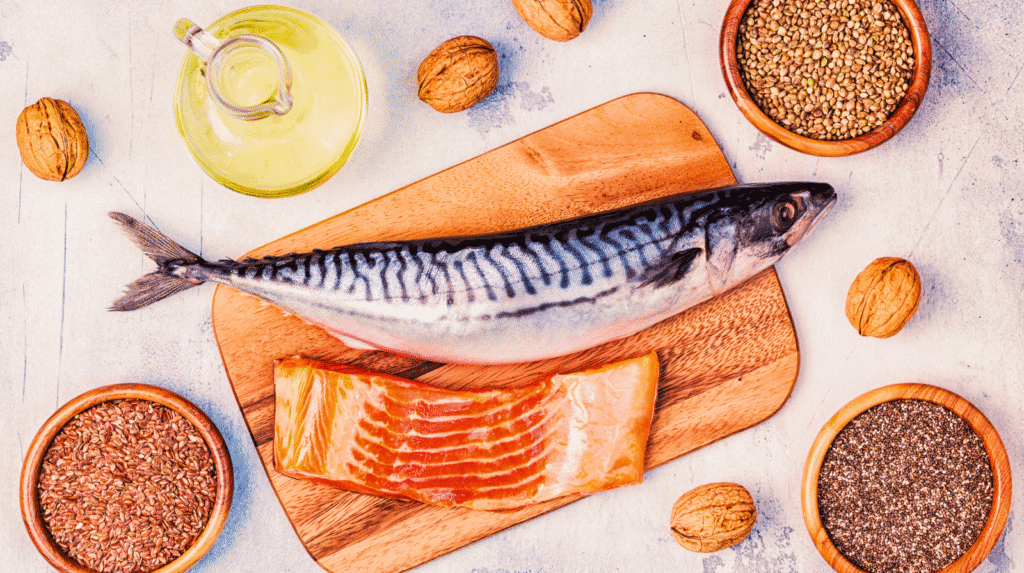 Omega-3-reiche Lebensmittel: Makrele, Lachs, Leinöl, Leinsamen, Chiasamen und Walnüsse auf einem Holzbrett