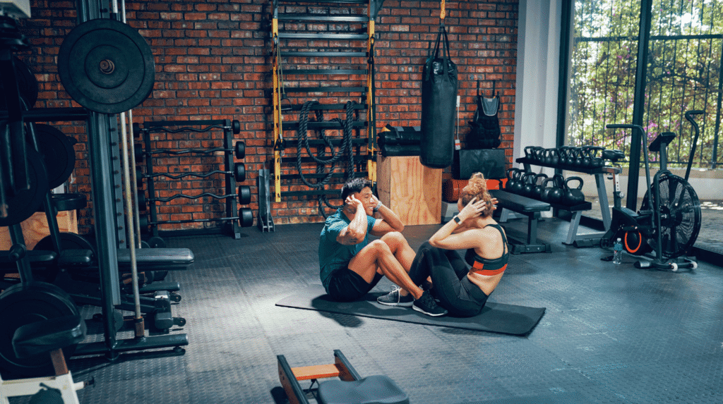 Zwei Erwachsene beim Krafttraining im Fitnessstudio – Bewegung und Muskelarbeit als Grundlage für nachhaltigen Fettabbau